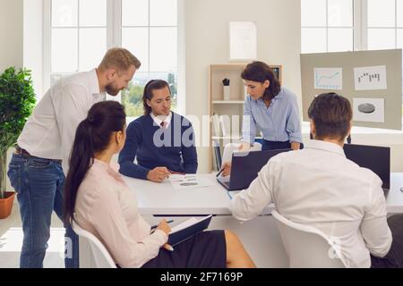 Department manager holding meeting with employees and analyzing financial reports in modern office Stock Photo