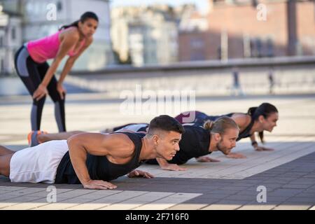 Young fitness men and women doing push-ups in the city Stock Photo