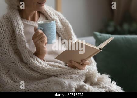 Old retired 70s lady reading book at home Stock Photo