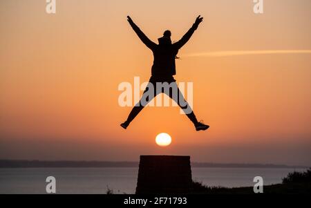 Bournemouth, UK. 4th April 2021.  Enjoying the moment as the sun rises on Easter Day at Hengistbury Head in Bournemouth, Dorset at the start of a bright and sunny day along the south coast. Credit: Richard Crease/Alamy Live News Stock Photo