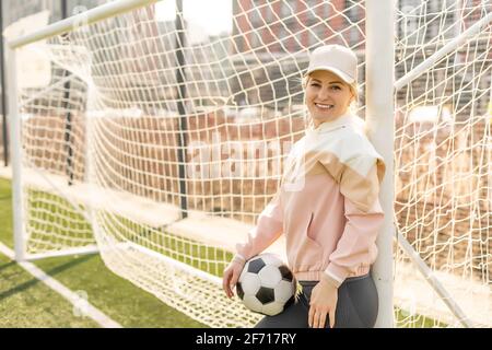 Pretty women's soccer. Young woman in sportswear with a soccer ball on the grass Stock Photo