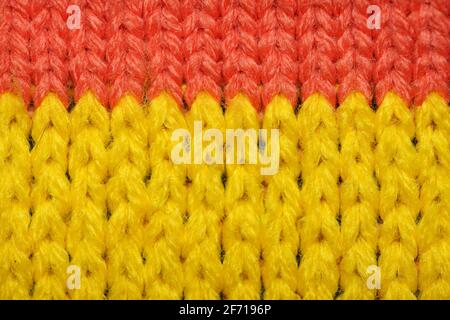 Yellow and red synthetic knitted fabric close up. Knitted fabric texture. Multicolor patterned knitted fabric texture. Background Stock Photo