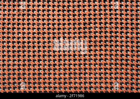 Synthetic knitted fabric with pattern elements of red, black and white yarns close up. Patterned knitted fabric texture background Stock Photo