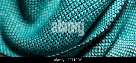 Synthetic knitted fabric with pattern elements of blue, black and white yarns close up. Patterned knitted fabric texture background Stock Photo