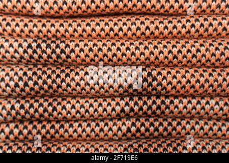 Stack of red knitted fabric, knitted winter clothes. Folded synthetic knitted fabric with pattern elements of red, black and white yarns close up. Mul Stock Photo
