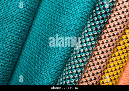 Stack of colorful knitted fabric, knitted winter clothes. Multicolored knitwear fabric background Stock Photo