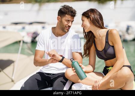 Man showing his marks to a woman on a sports watch after exercise. People using smartwatch. Stock Photo