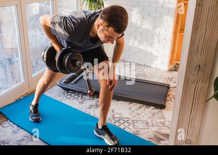 Athletic man doing dumbbell one arm row exercise Stock Photo
