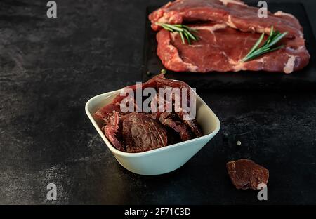 Jerky snack high in protein from lean beef. smoked, dried food with meat cuts and pepper.  Stock Photo