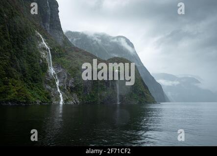 Waterfalls in Milford Sound with Southern Rata forest in bloom Stock Photo