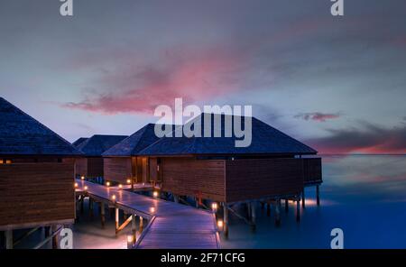water villas with a purple sunset over the ocean. Stock Photo