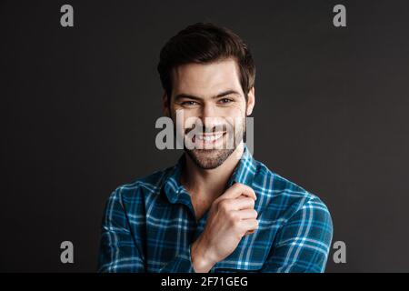 Joyful handsome guy smiling and looking at camera isolated over black background Stock Photo