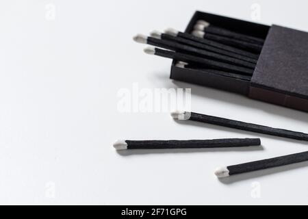 Black matches in matchbox on white background. Stock Photo