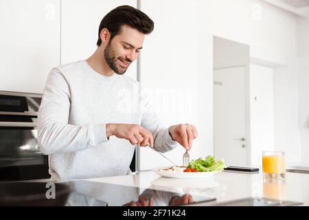 Happy handsome man smiling while having breakfast at home kitchen Stock Photo