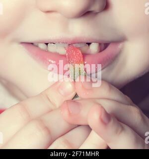 The child is eating jelly candy worms. Stock Photo