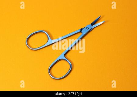 Small metal manicure scissors on yellow background. Stock Photo