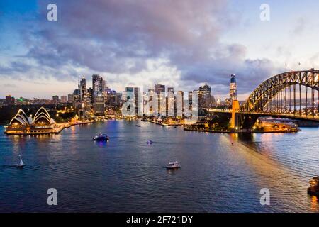 Bright waterfront of City of Sydney urban skyline around Circular quay on Harbour near Bridge - aerial view. Stock Photo