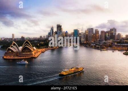 Urban skyline of Sydney city CBD around Circular Quay at sunset - aerial view over passenger ferry. Stock Photo