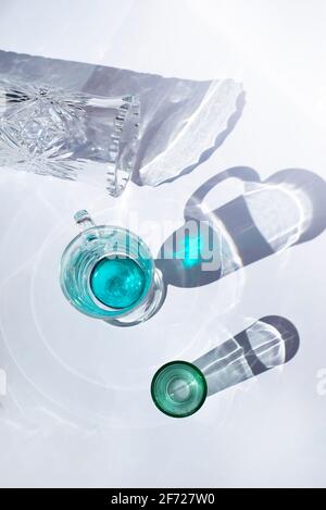 Various glassware on a white background illuminated with light. Faceted vase. Green glass and turquoise glass circle. Stock Photo