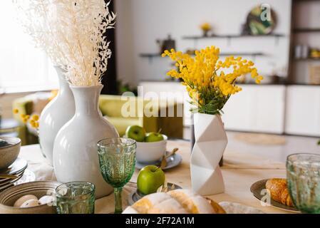 Bright spring mimosa in a ceramic geometric vase in the decor serving a festive or home table in the kitchen Stock Photo