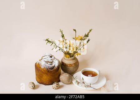 Easter composition with kulich and eggs with spring flowers on beige background. Easter holidays breakfast concept. Stock Photo