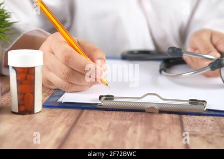 female doctor hand writing prescription on desk, close up. Stock Photo