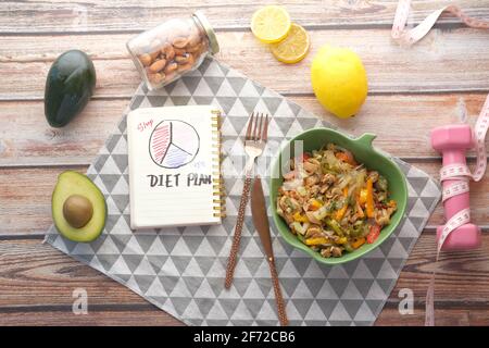 Diet plan with healthy meal and dumbbell on wooden background  Stock Photo