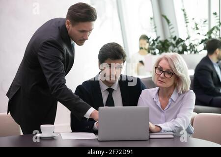 Diverse colleagues brainstorm using computer at meeting Stock Photo