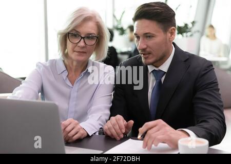 Diverse employees work on laptop discuss business ideas Stock Photo
