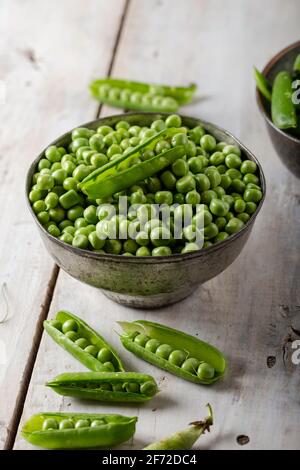 Fresh green peas. Fresh green peas pods and green peas in bowl on wooden background. Stock Photo