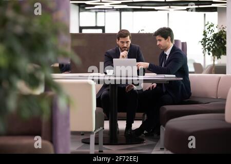 Pensive businessmen cooperate on laptop in office Stock Photo