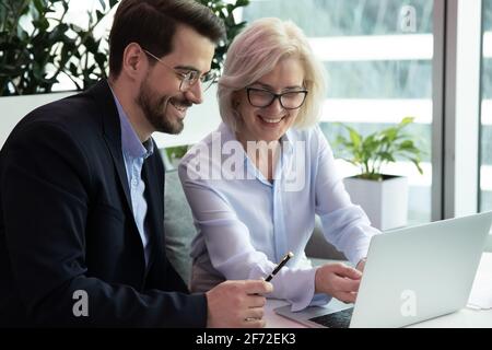 Smiling diverse colleagues brainstorm on laptop at workplace Stock Photo