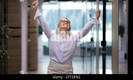 Excited middle-aged female employee celebrate success in office Stock Photo