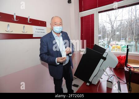 People with masks are voting electronic on a machine for Bulgarian parliamentary elections in Sofia, during coronavirus pandemic, in Sofia, Bulgaria o Stock Photo