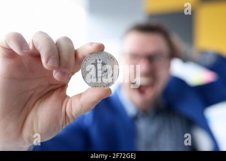 Joyful businessman holding coin with bitcoin logo Stock Photo