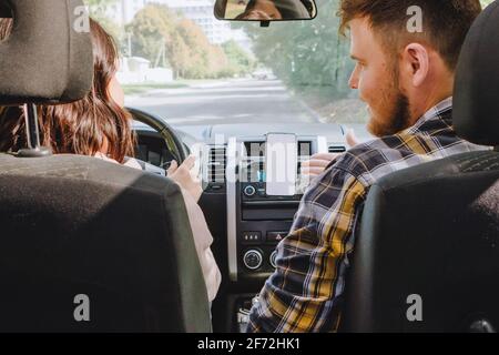man with woman in car using phone for navigation white empty screen Stock Photo