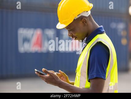 African American black men workers playing, online chatting or browsing on mobile phone while taking a break at construction site Stock Photo