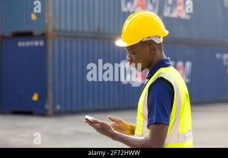 African American black men workers playing, online chatting or browsing on mobile phone while taking a break at construction site Stock Photo