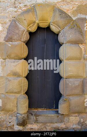 Old ancient black wooden door framed with big sandstone archway Stock Photo