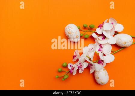 White Easter eggs and flowers on orange background. Spring holidays concept Stock Photo
