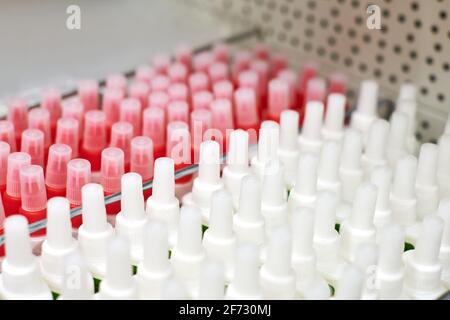 White and red plastic bottles with glue. Abstract background. Bottles with glue on shelf in office supply store. Selective focus. Stock Photo