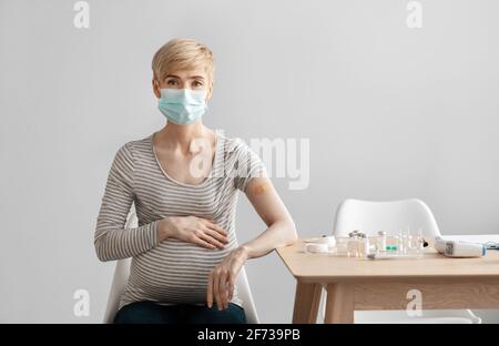 Mature pregnant woman patient in protective mask sits at table with equipment Stock Photo