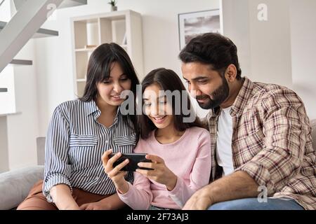 Happy indian family and teen daughter using smart phone at home. Stock Photo