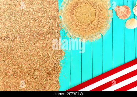 Beach layout. Pebbled sand with azure wooden pier or sun lounger or towel. Red-white sunbed, straw hat, seashells. Travel and tourism. Copy space Stock Photo