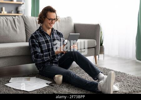 Cheerful Man Using Tablet Computer Browsing Internet Sitting At Home Stock Photo