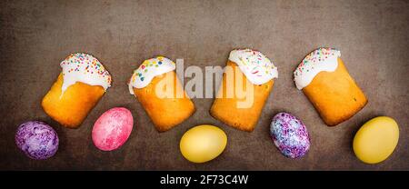 Easter cakes and Easter colored eggs on a dark background. Religious holiday of bright Easter. Stock Photo