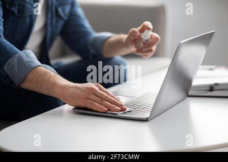 Male hands using disinfectant spray for cleaning laptop, closeup Stock Photo