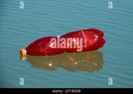 Red plastic bottle floating on the surface water Stock Photo