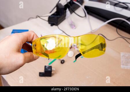 Yellow protection glasses in hand on the desktop close up Stock Photo