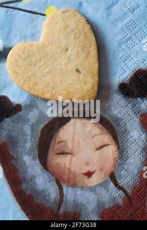 heart shaped Lavender Shortbread from Waitrose & Partners on  serviette napkin with girl holding hands up - shortbread biscuit with lavender Stock Photo